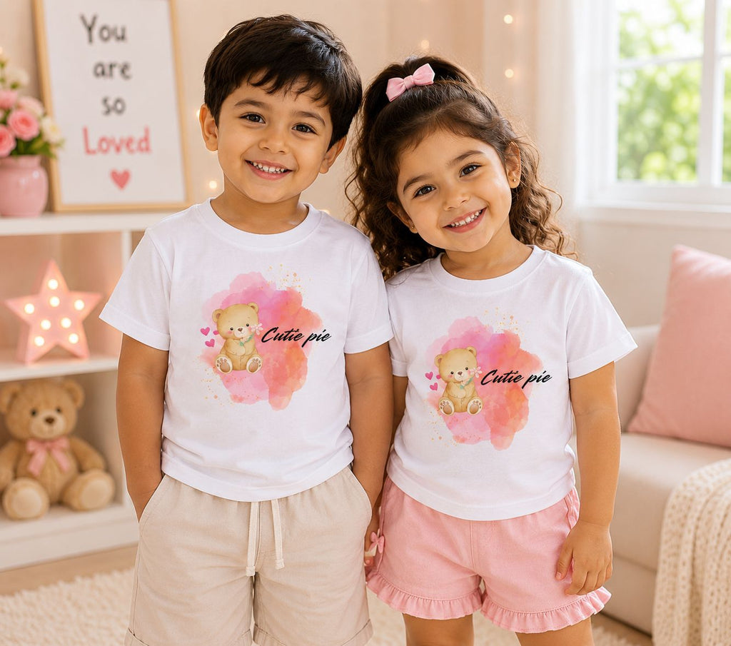 Toddler boy and girl wearing matching white Cutie Pie Duo teddy bear graphic tees indoors